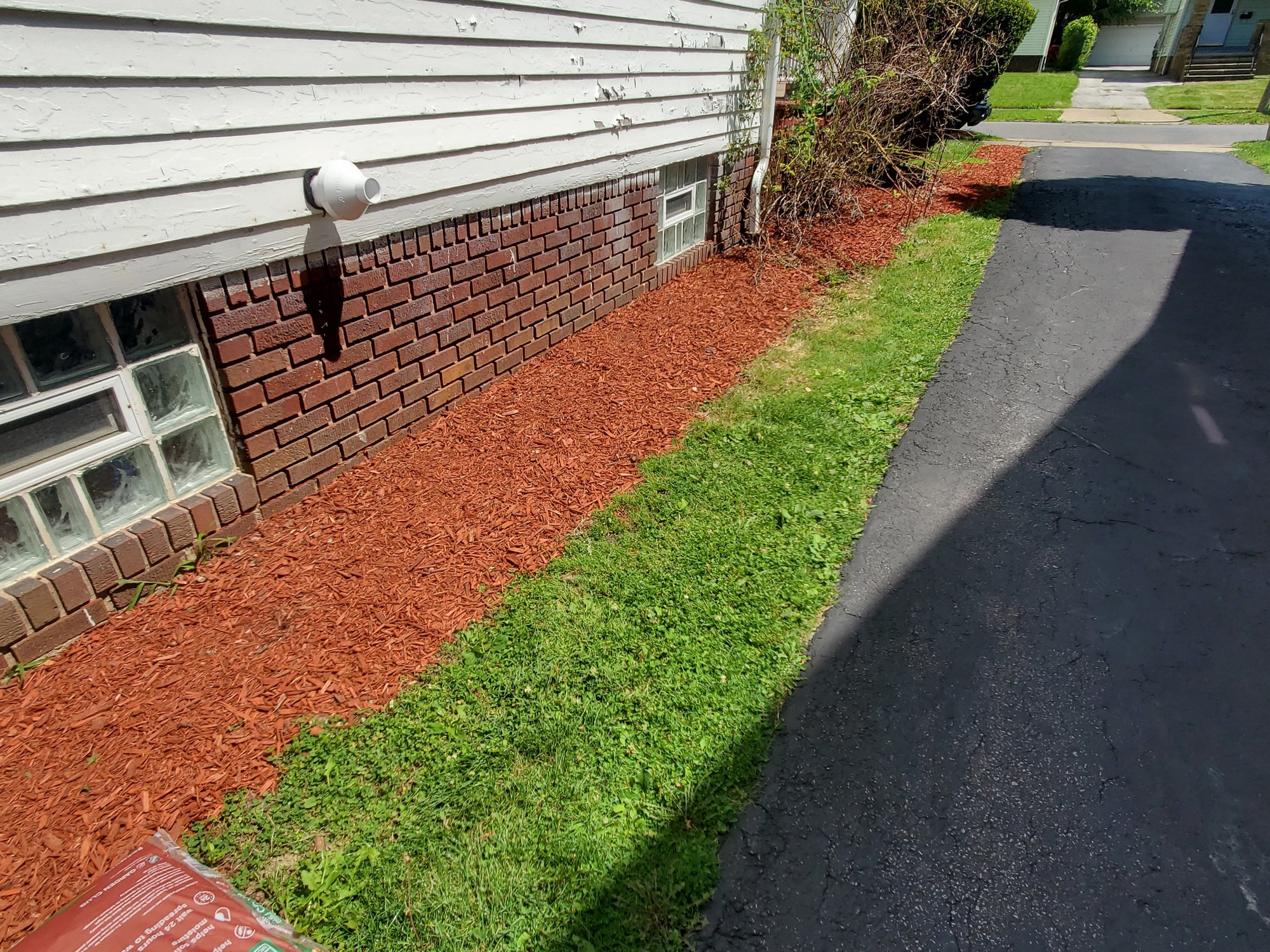 The right side of a home in Euclid, OH, has red mulch applied along the border by Kevin J Services.