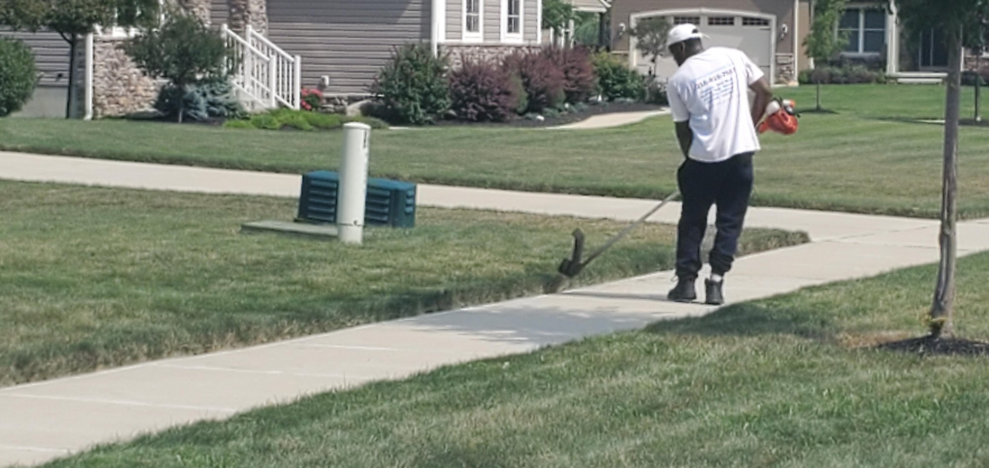 An employee of Kevin J Services is edging the lawn after he has mowed the front lawn of a customer in Euclid, Ohio.